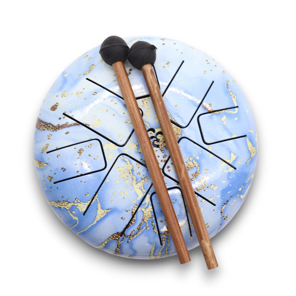 tambor hapi drum instrumento musical para rituales color azul cielo 18 cm con palitos para tocar encima, fondo blanco neutro